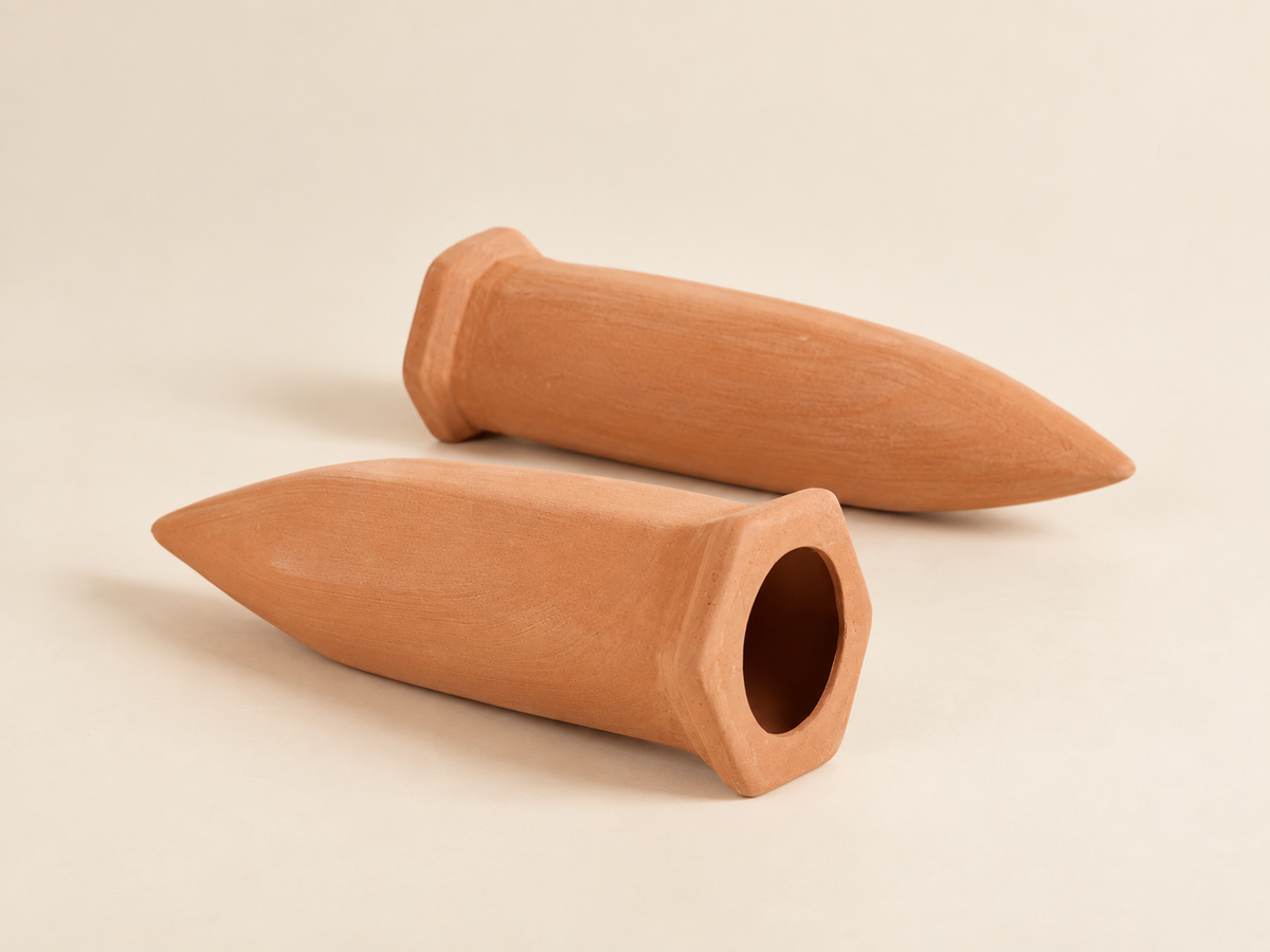 Terracotta watering spikes on a soft beige studio background