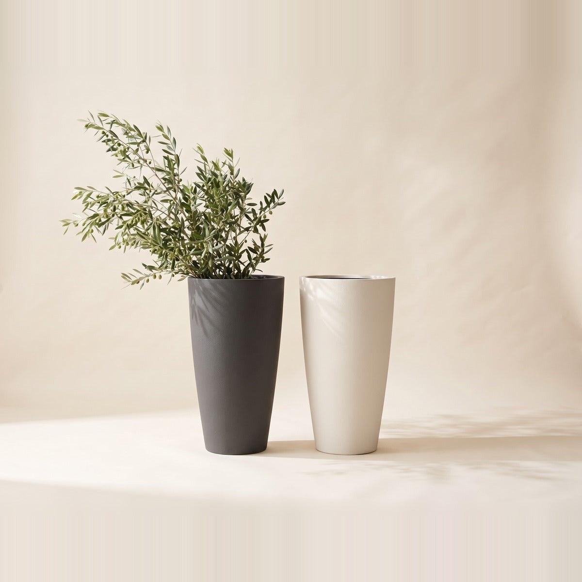 Fiberglass & Fiber Clay Planters — three tall matt fiber clay and fiberglass planters in stone grey, cream and charcoal, one with a tall green plant