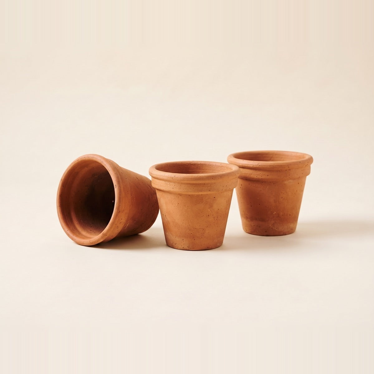 Terracotta & Clay Pots — five unglazed terracotta clay pots of different sizes and shapes stacked and arranged, one with a small green plant